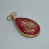 Pendant: pink and gold inks in tear-shaped bezel, domed with resin