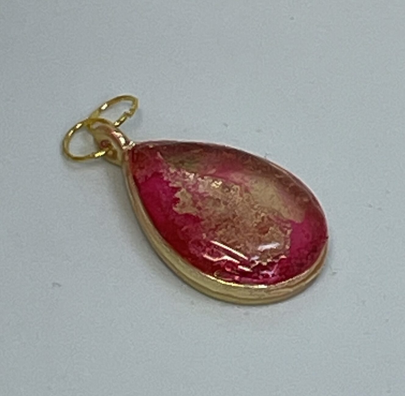 Pendant: pink and gold inks in tear-shaped bezel, domed with resin