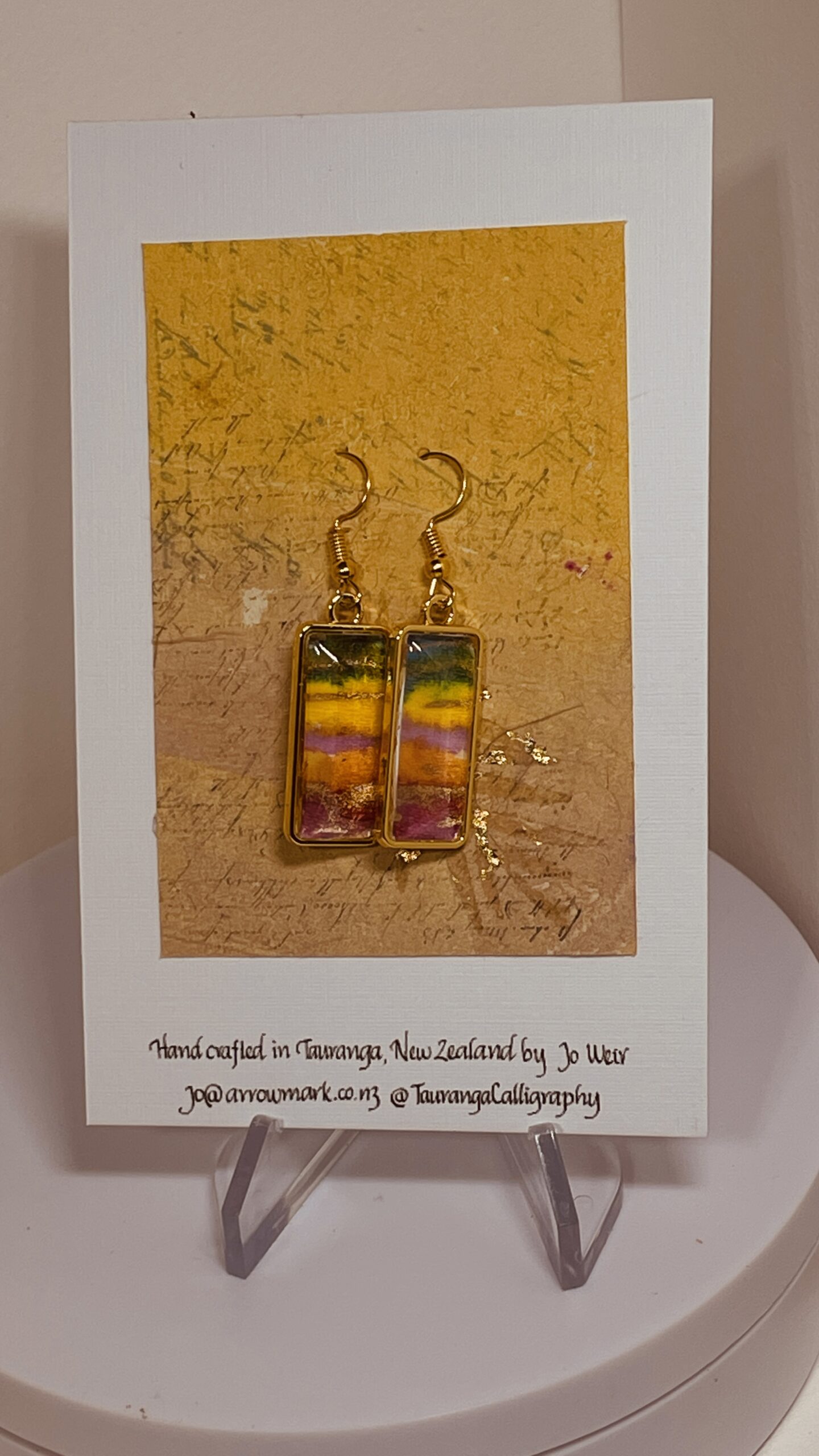 Hand made earrings in gold, green and yellow stripes on tissue, beneath glass domes