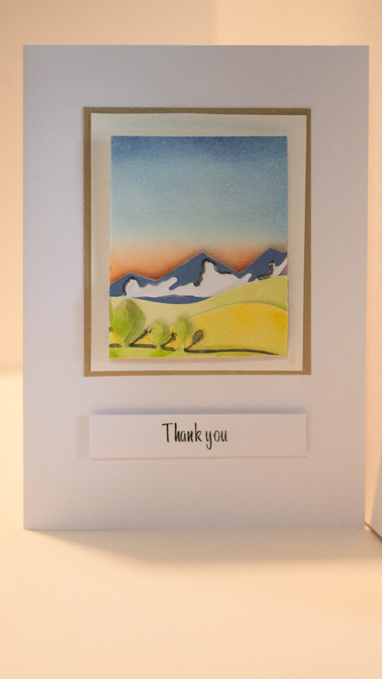 Hand crafted thank you card featuring a hand painted sunset backdrop with 3D mountains, hills and trees. 