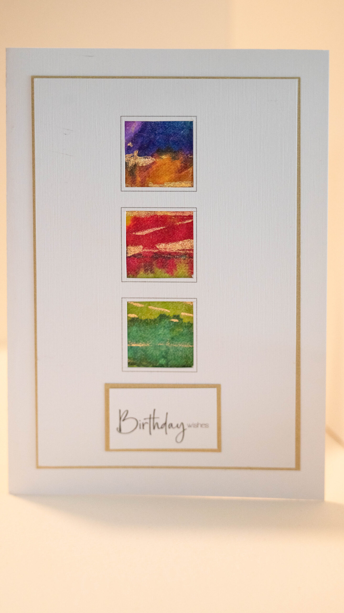 Hand coloured tissue backround with a vertical triptych in blues, reds and greens with gold accents. 