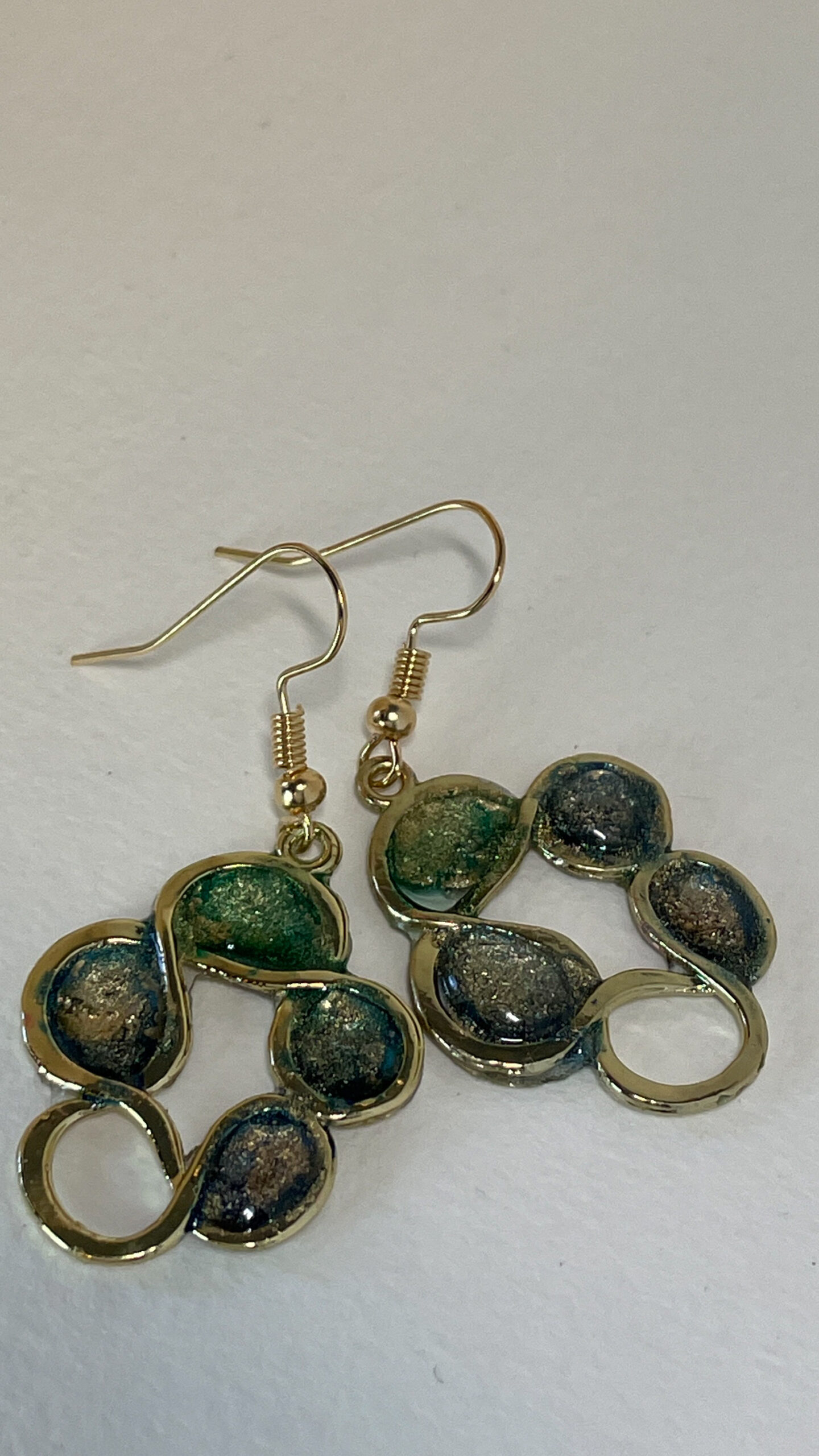 Hand made earrings crafted from ink and resin set in gold wreath-shaped bezels.