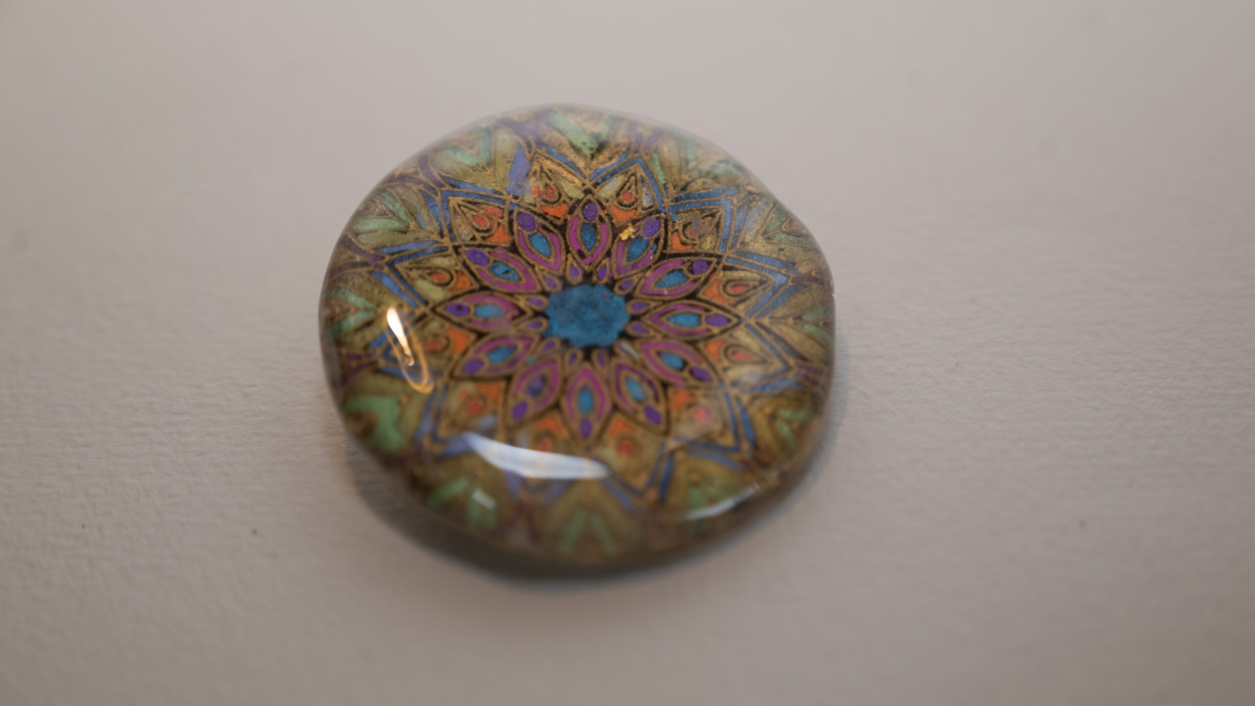 Tauranga Jewellery Brooch featuring gold embossed mandala hand coloured with metallic paints and protected with a resin layer