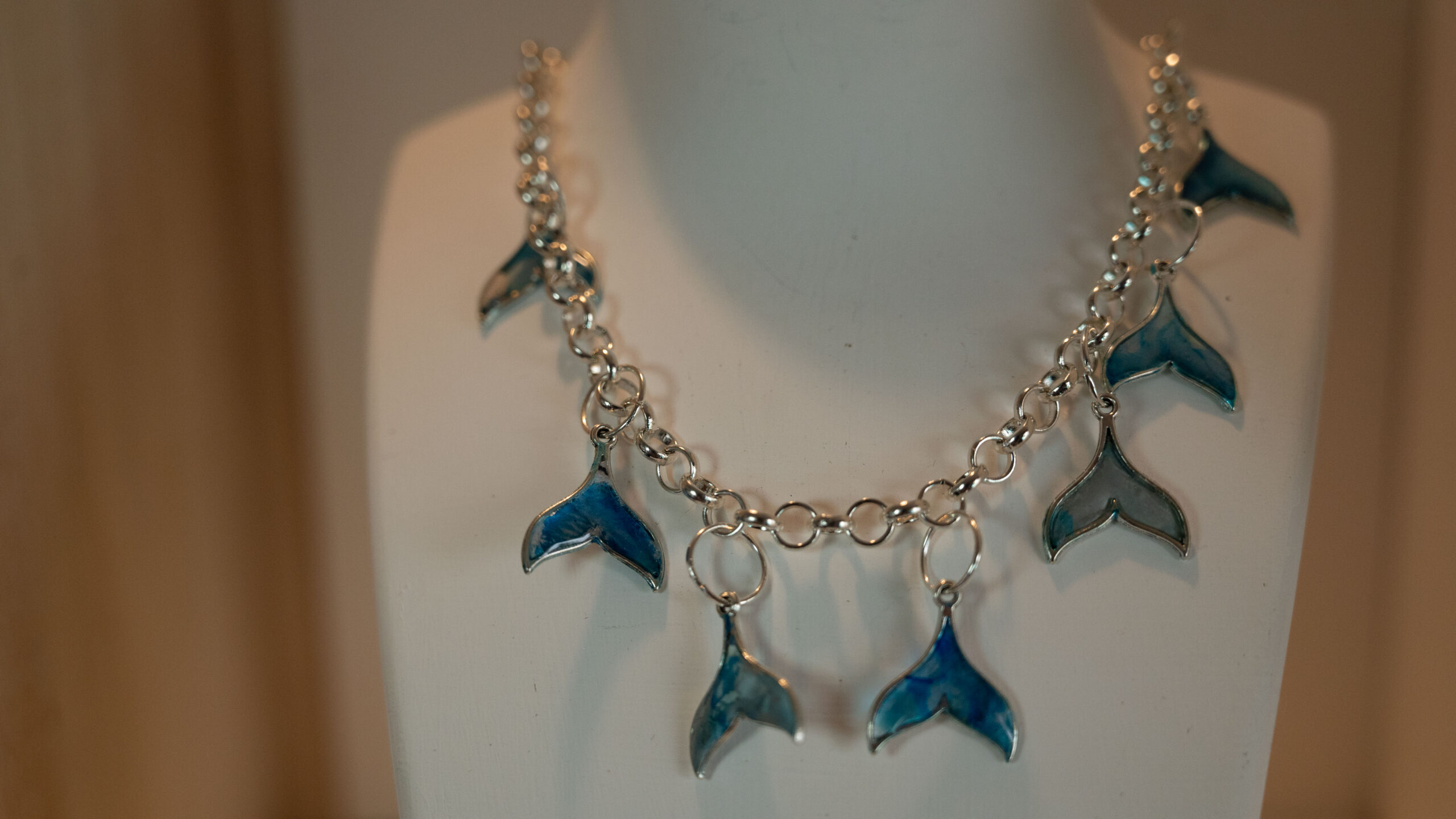 Tauranga Jewellery: Whale Tail Necklace. Silver-coloured ink and resin whale tails hand crafted and hung from a silver coloured chain link necklace.