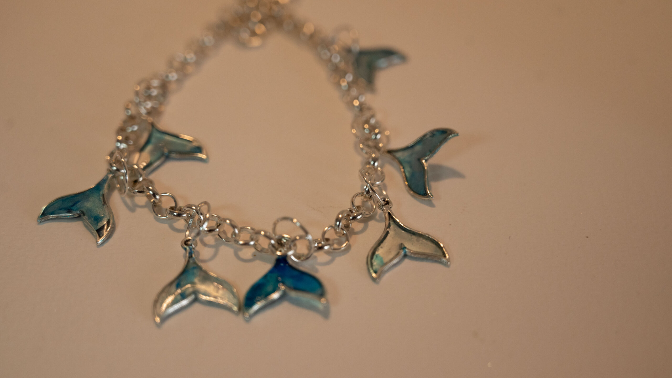 Tauranga Jewellery: Whale Tail Necklace. Silver-coloured ink and resin whale tails hand crafted and hung from a silver coloured chain link necklace.