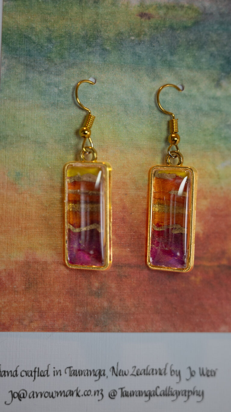 Tauranga Jewellery: hand crafted earrings featuring gold, pink and orange hand-inked tissue set in a gold coloured bezel and topped with a cabochon