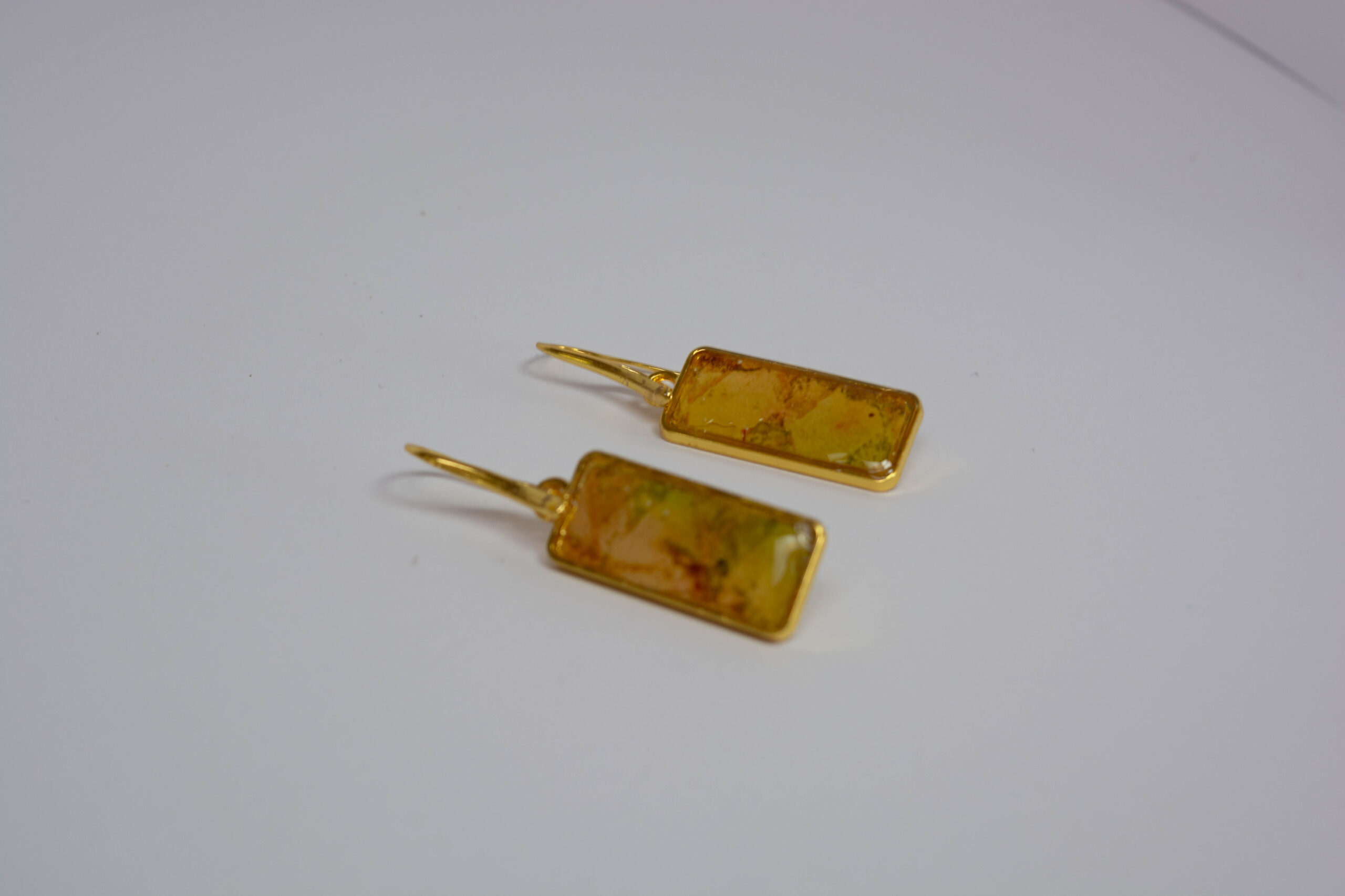 Hand crafted earrings ing golds, greens and yellows. Ink, resin and metal.