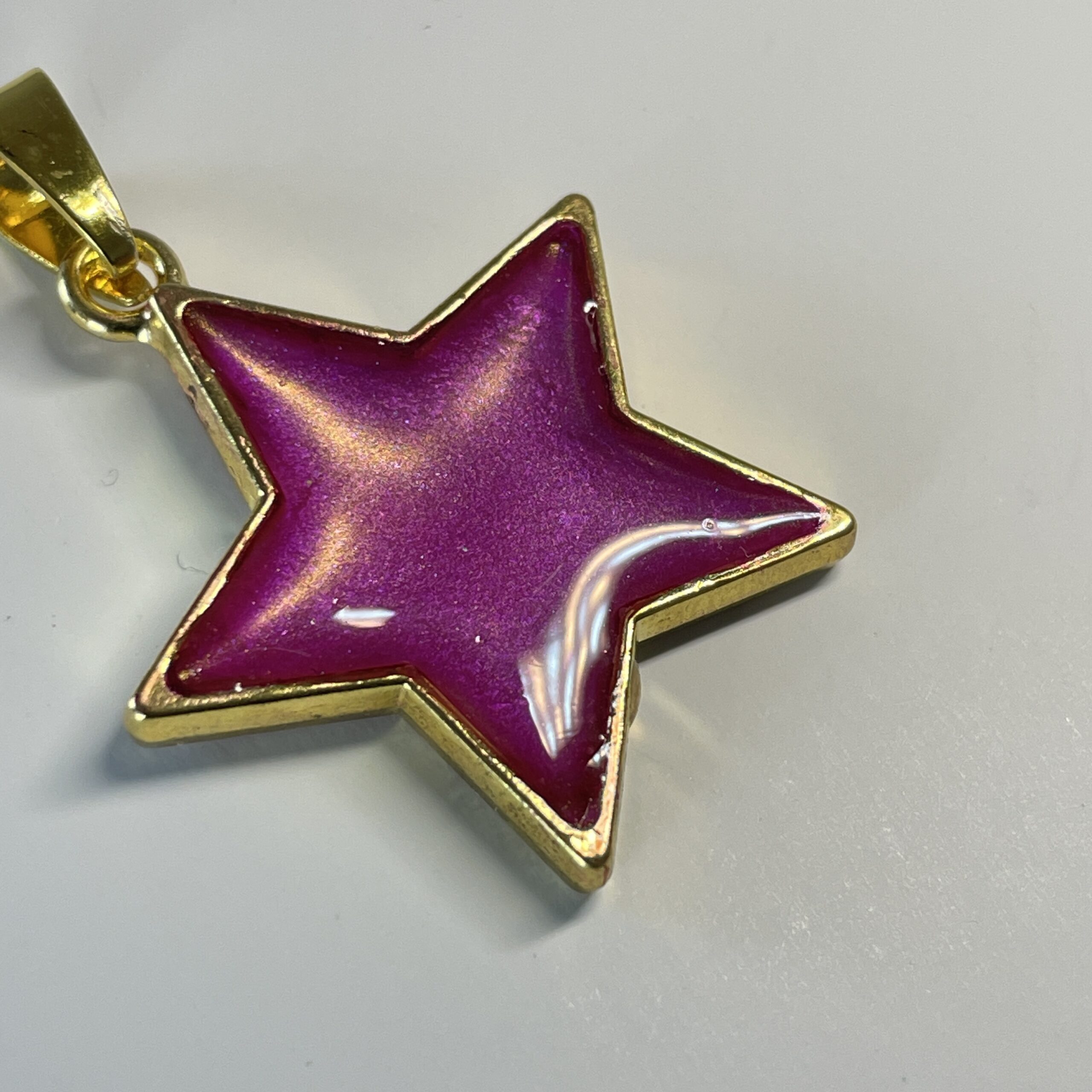 Hand made pendant featuring an irridescent pink star
