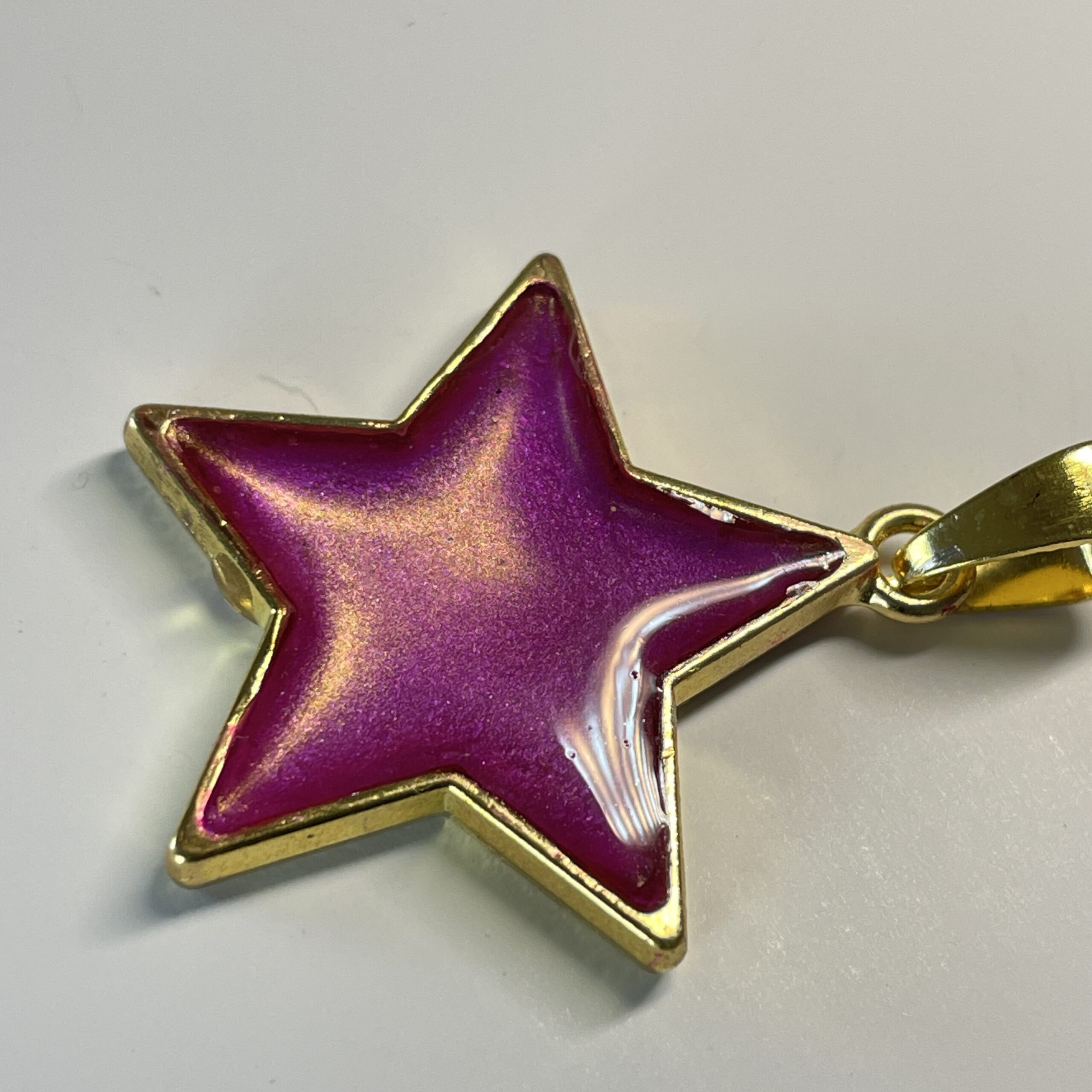 Hand made pendant featuring an irridescent pink star
