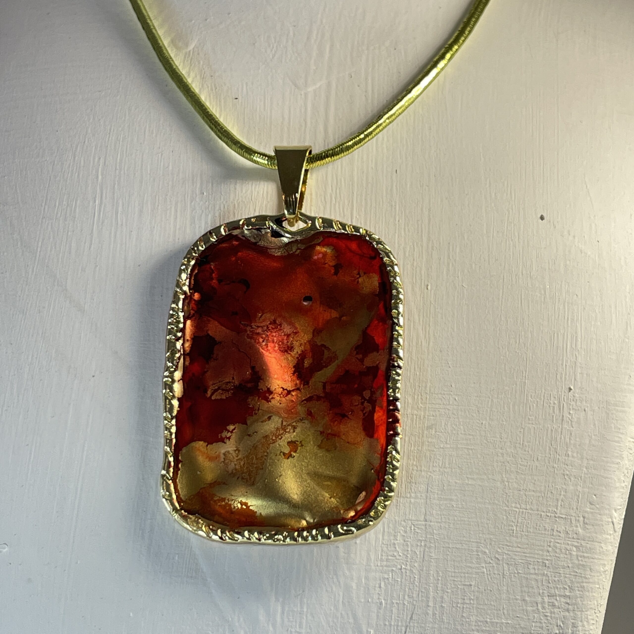 this hand made pendant features red, yellow and gold pignments