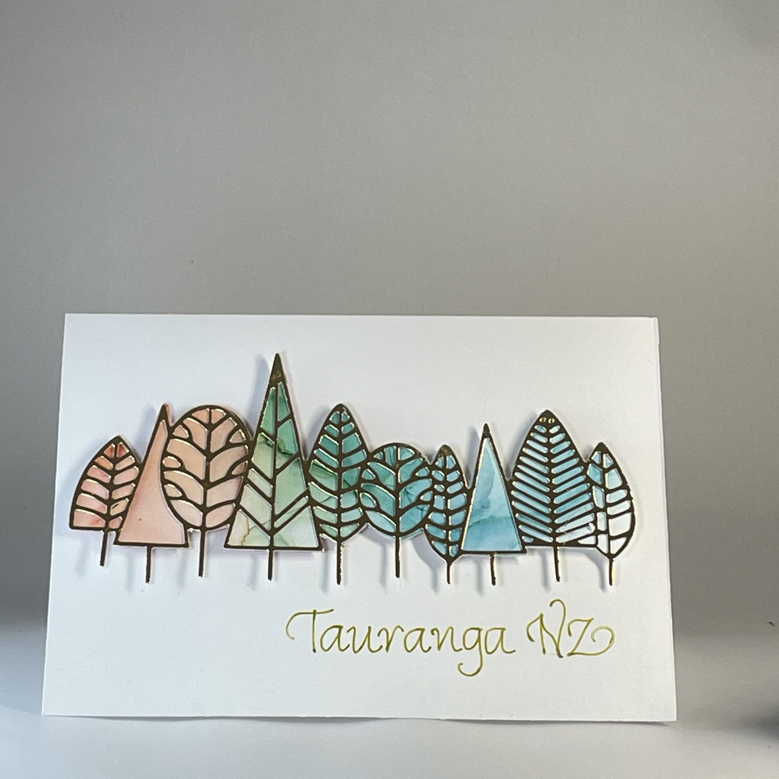 Hand Made Tauranga Card Hand made greeting card featuring die cut gold trees filled with alcohol ink art and calligraphy text "Tauranga, NZ".