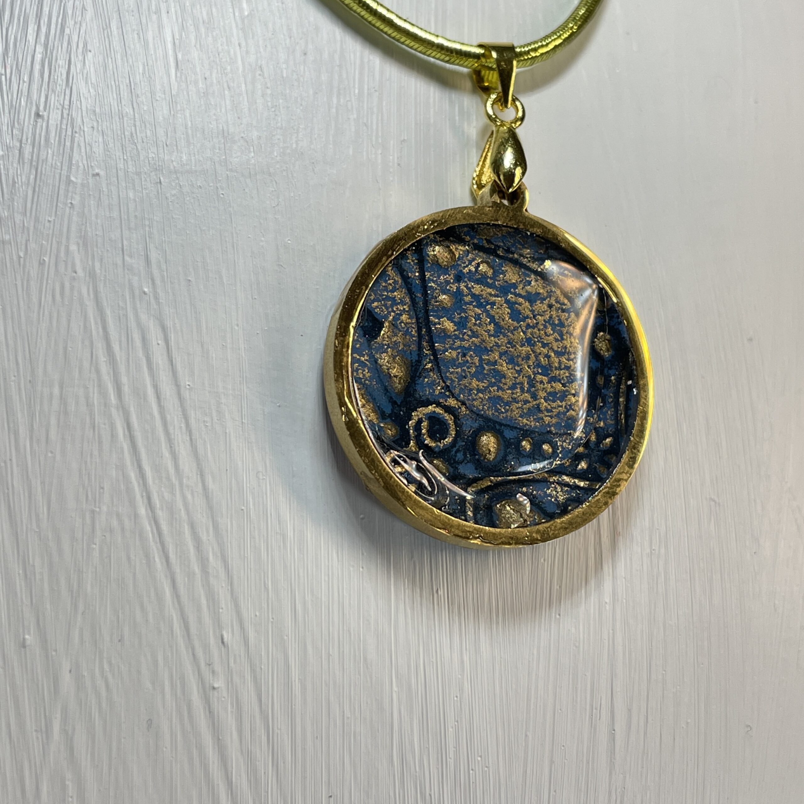 Hand made in Tauranga, this pendant is crafted from paper, ink, resin and metal. It's perfect to pair with blue outfits.