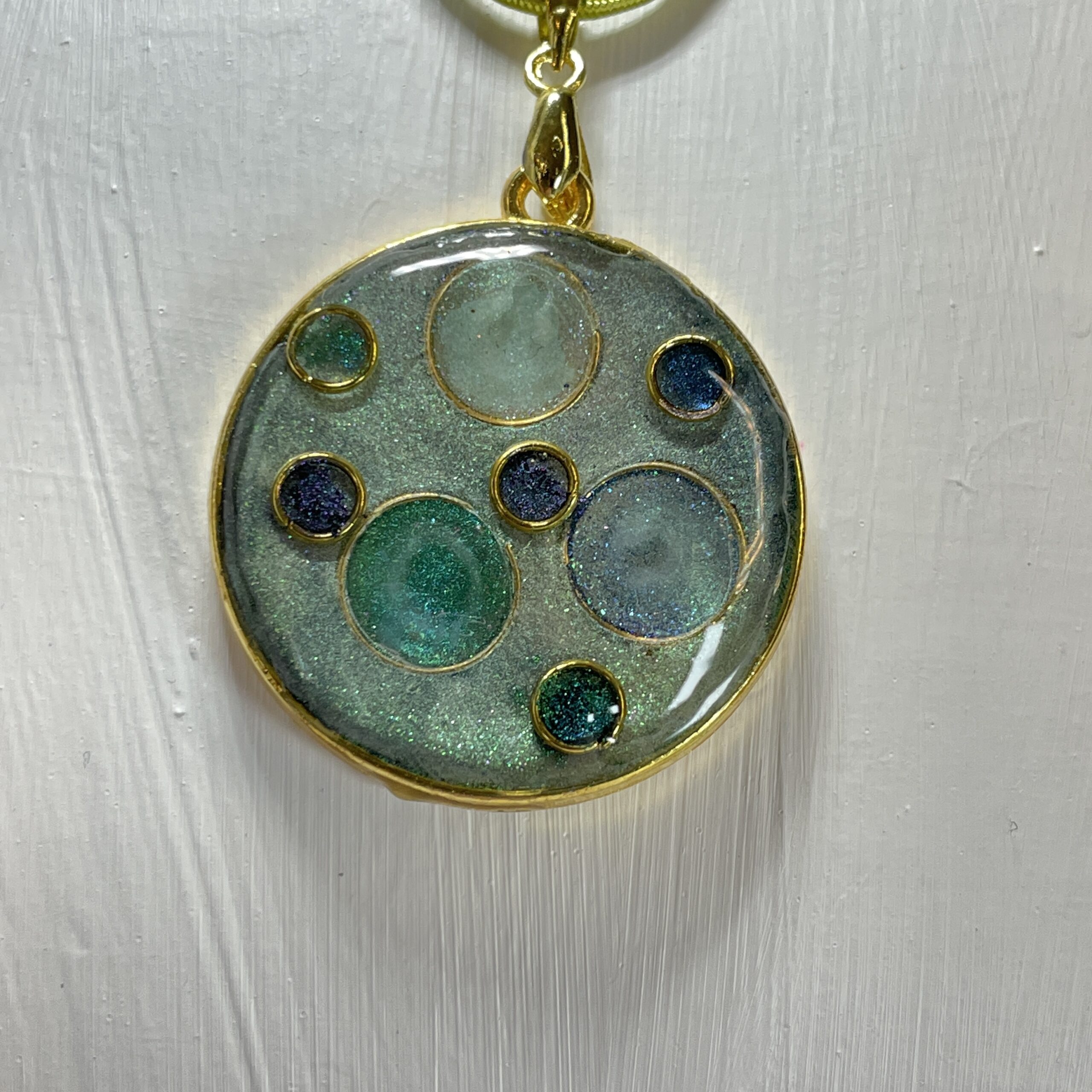 hand made pendant in greens and teals featuring metal and resin
