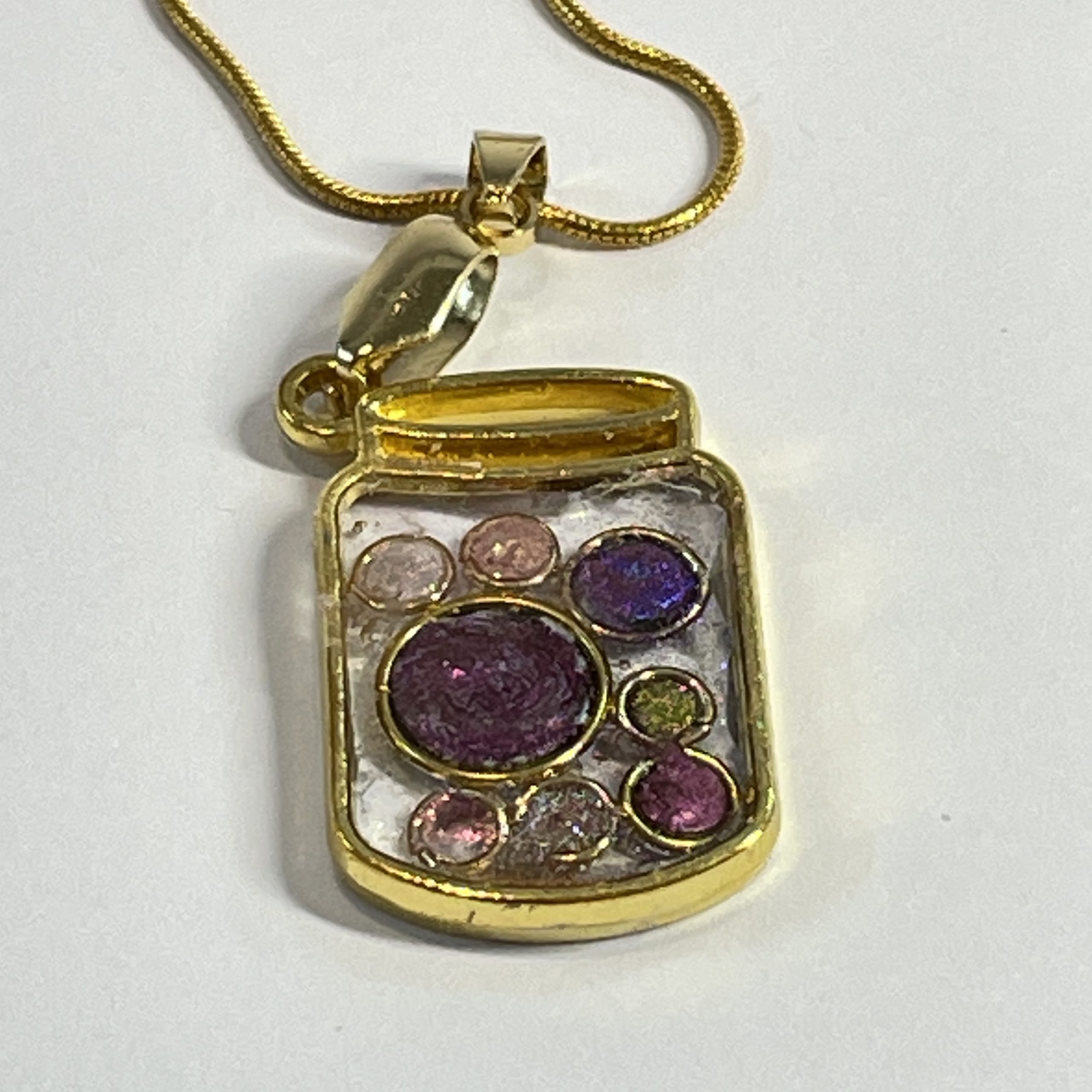 Hand made jar pendant featuring hand crafted sparkly bubbles encased in gold coloured metal Hand made jar pendant featuring hand crafted sparkly bubbles encased in gold coloured metal