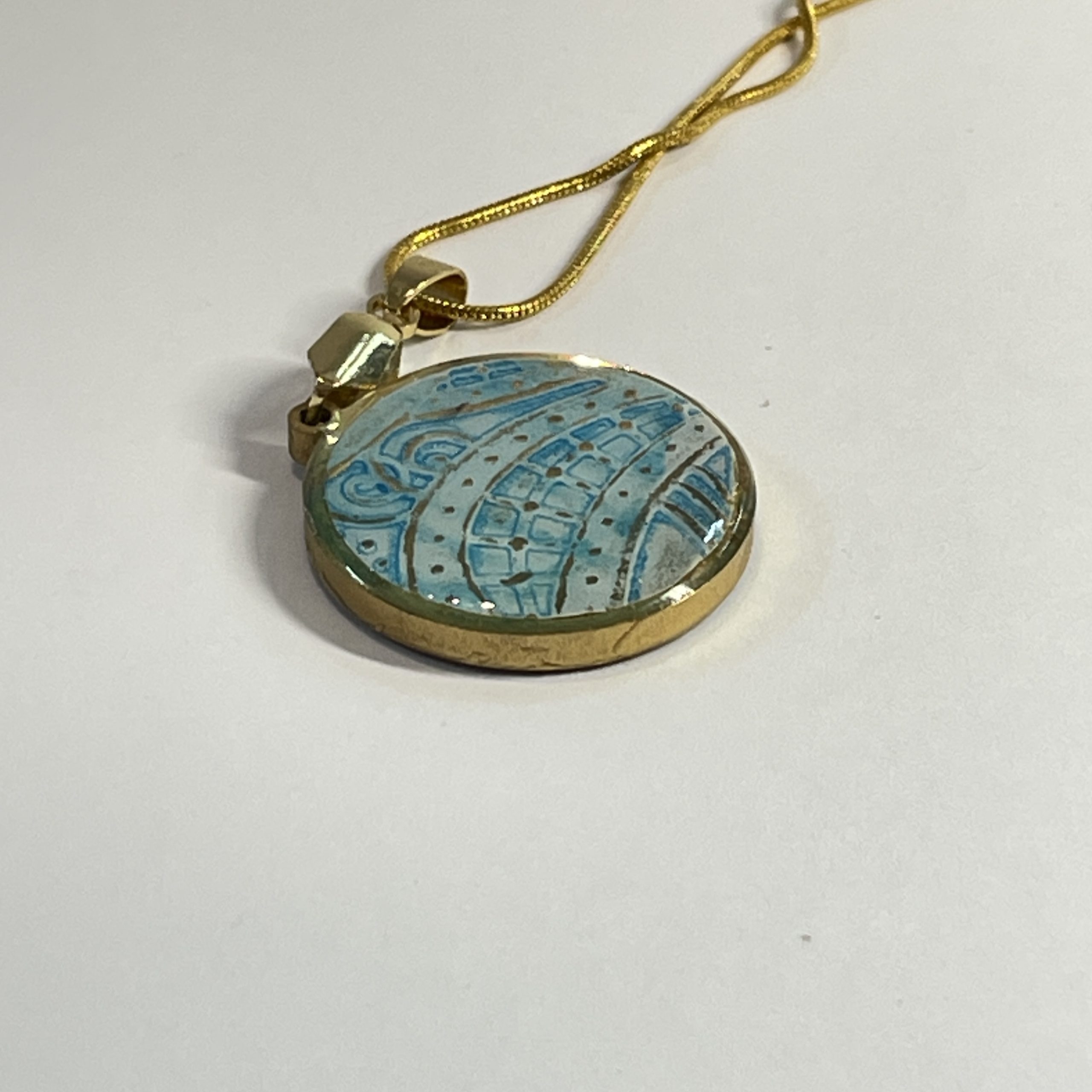 Pendant: double sided round pendant, each side containing a round piece of hand painted and embossed paper, yellow one side, blue the other