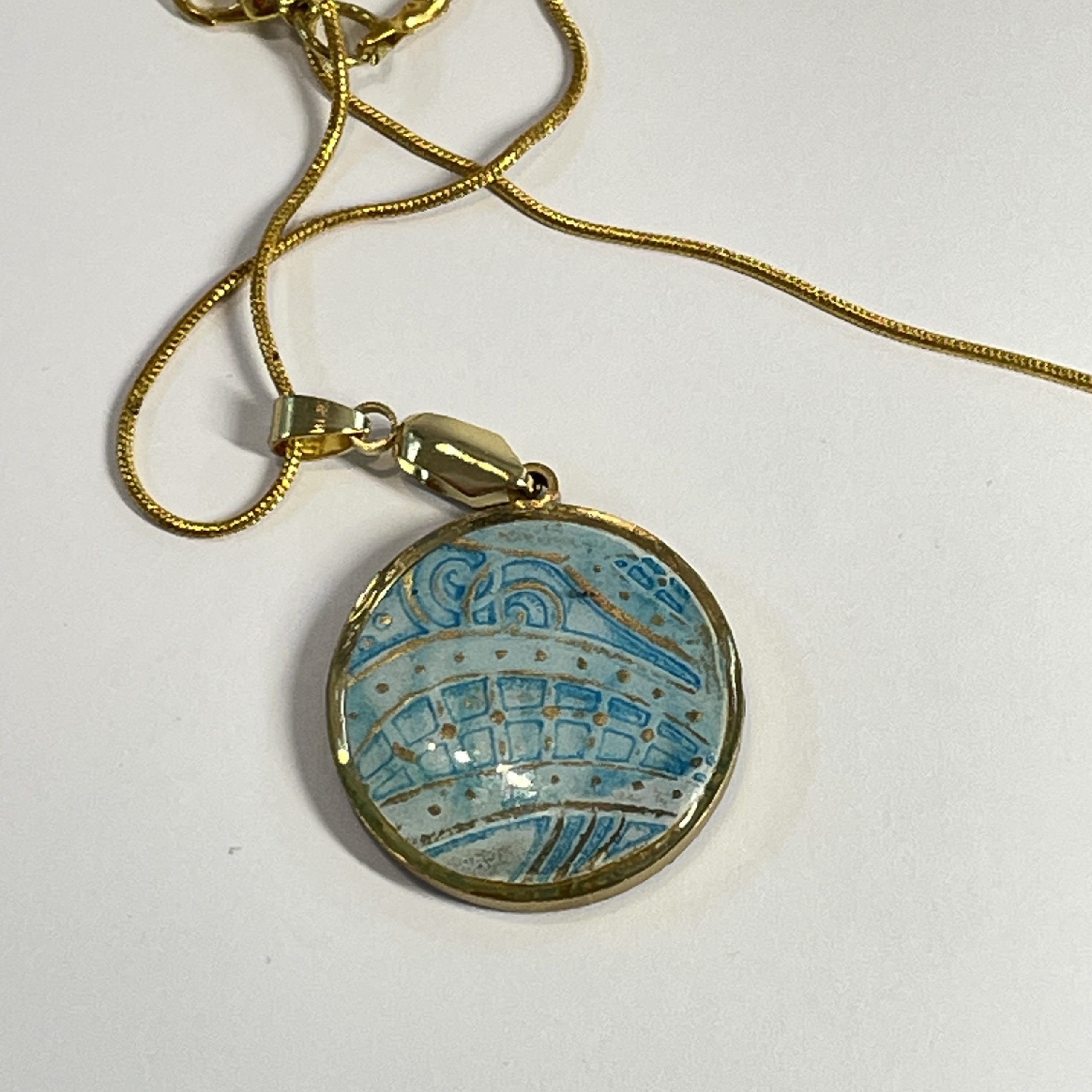 Pendant: double sided round pendant, each side containing a round piece of hand painted and embossed paper, yellow one side, blue the other